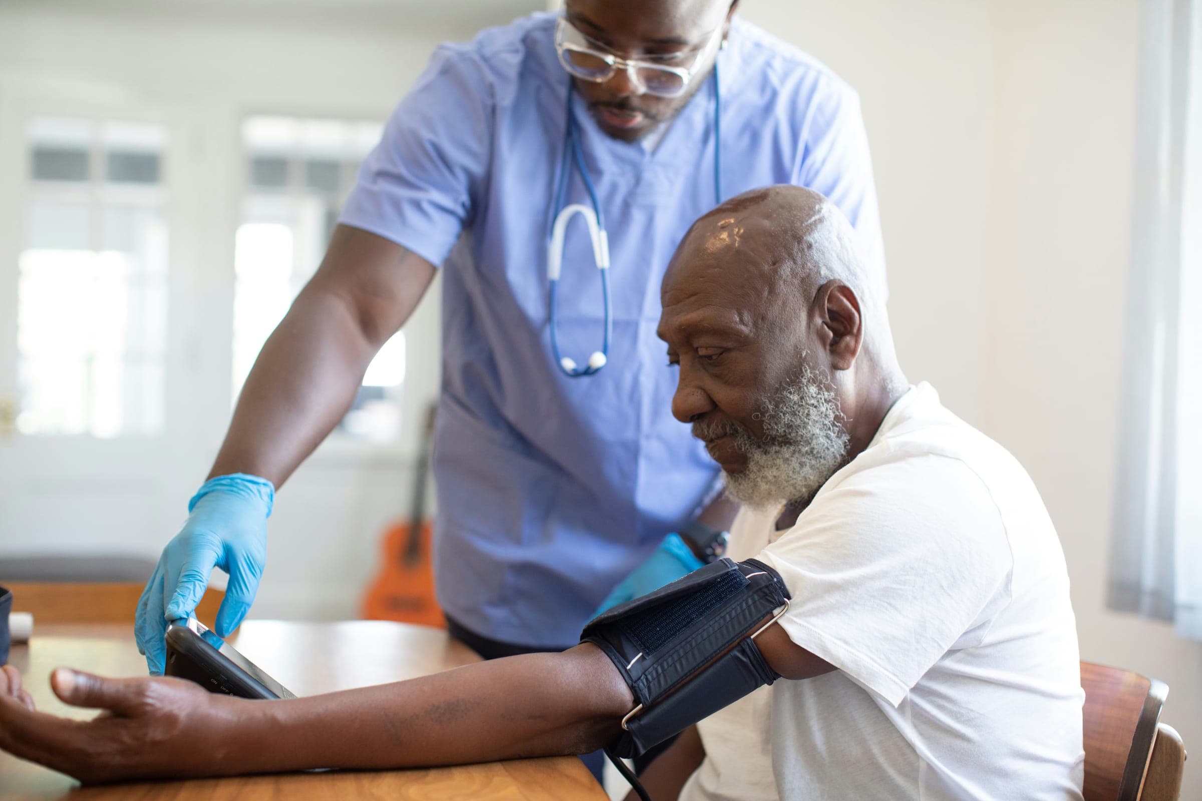 A nurse taking an older man's blood pressure during a home visit